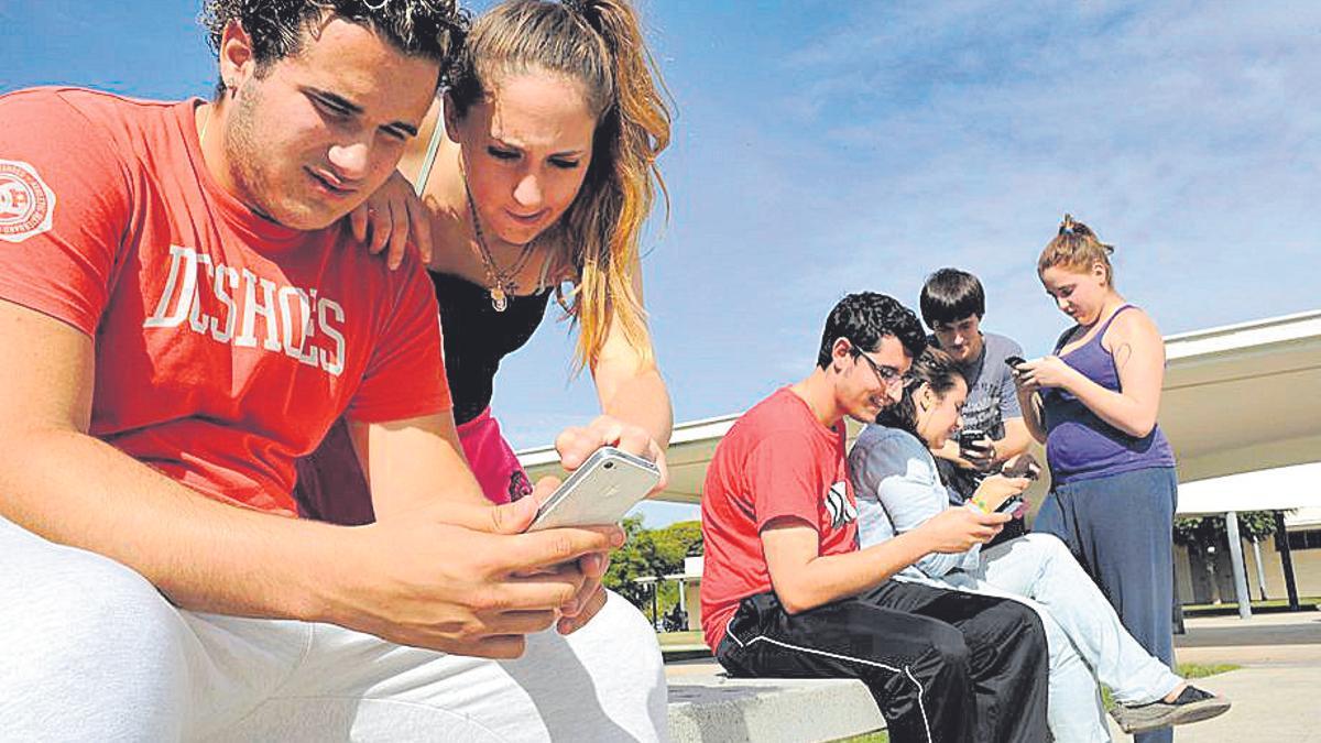 Unos jóvenes miran sus teléfonos móviles.