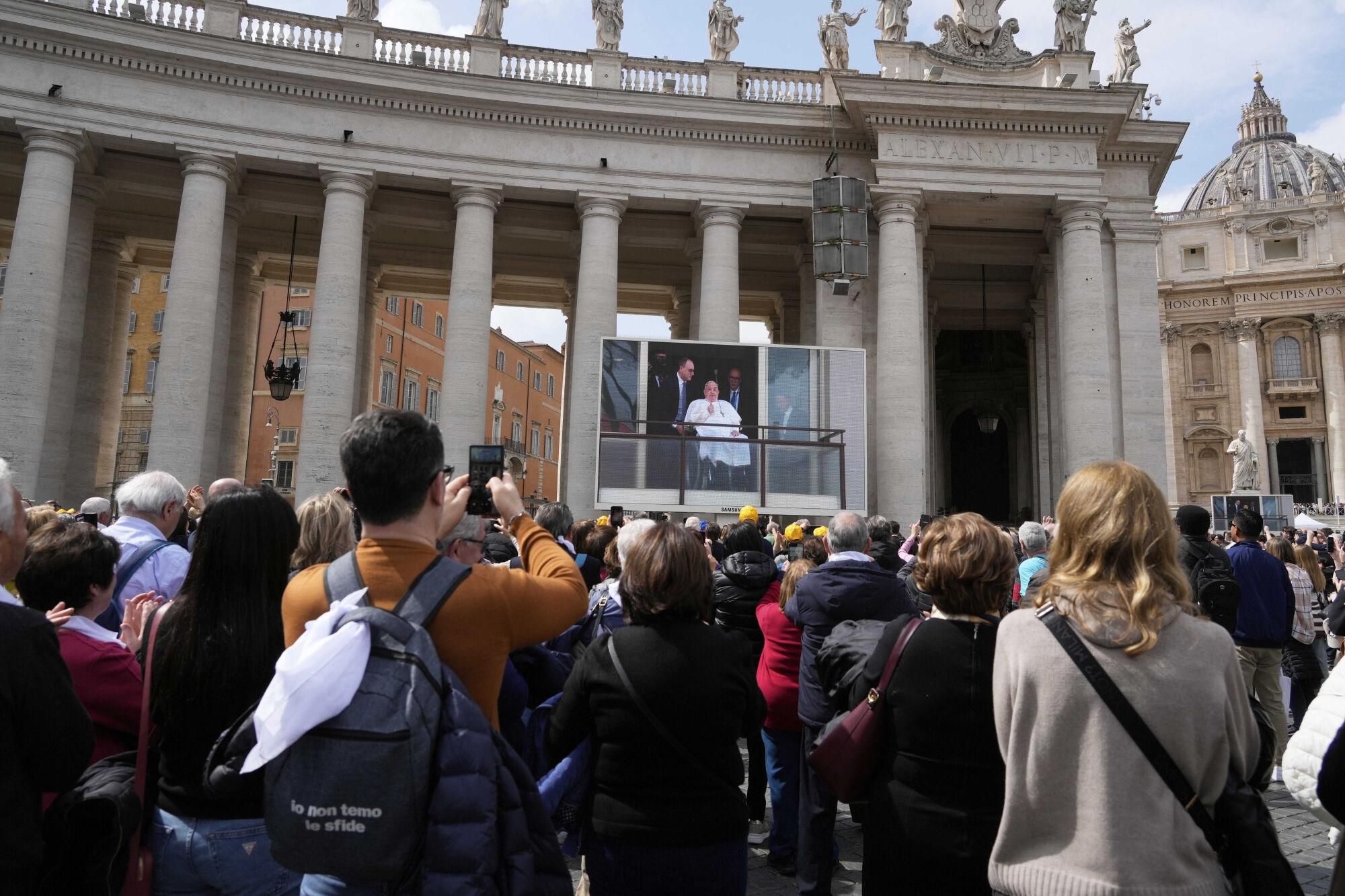 Faithful and pilgrims gather in St. Peter's Square at The Vatican to follow on giant screens a live broadcast from Rome's Agostino Gemelli Polyclinic, Sunday, March 23, 2025, where Pope Francis made his first public appearance since he was hospitalized on Feb. 14 with bilateral pneumonia. (AP Photo/Gregorio Borgia). EDITORIAL USE ONLY/ONLY ITALY AND SPAIN