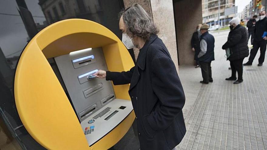 Víctor Feliu, de la Plataforma de Gent la Gran de Manresa, en un dels caixers automàtics de la ciutat