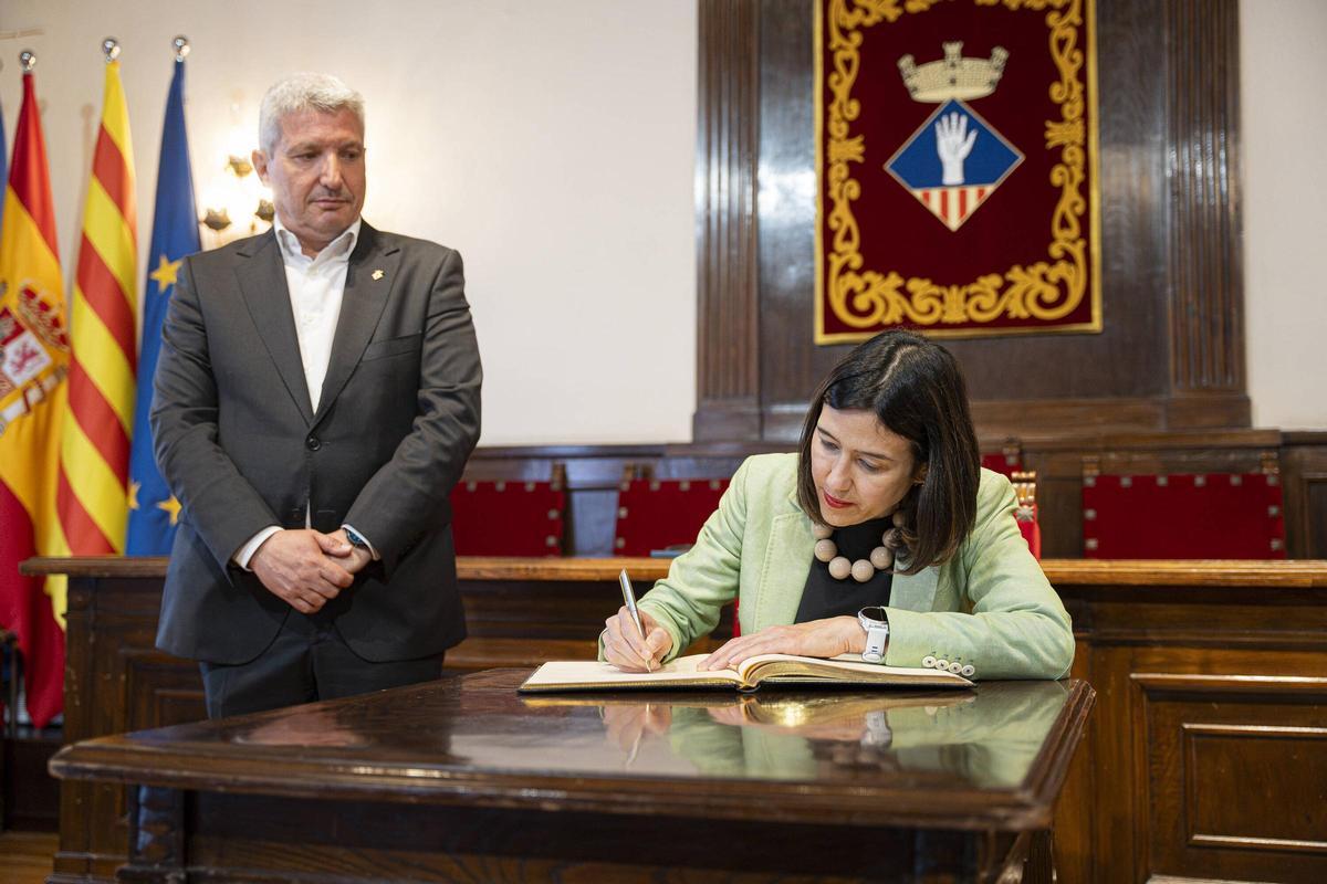 La consellera de Interior, Núria Parlon, firma en el libro de honor de Esplugues ante la mirada del alcalde, Eduard Sanz