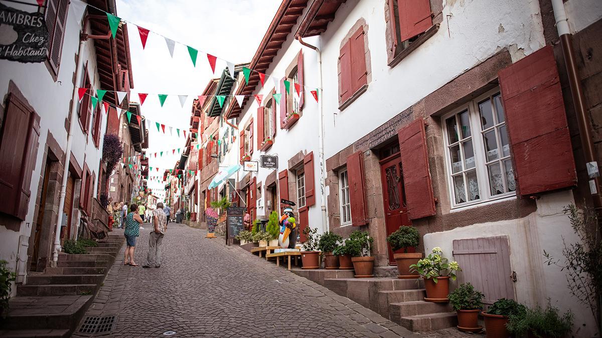 Calle empedrada de Saint-Jean-Pied-de-Port, con casas tradicionales de contraventanas rojas y ambiente local que resume la esencia del interior del País Vasco francés.