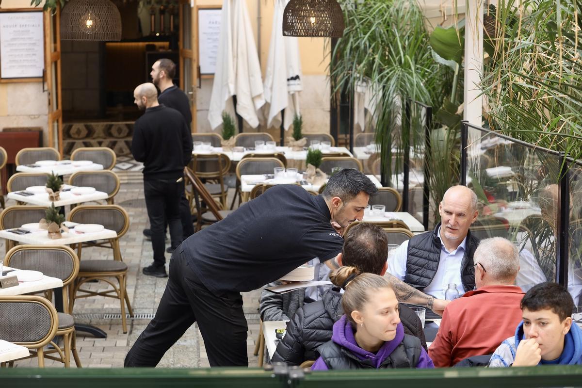 Un camarero atiende a unas clientes en un establecimiento en Málaga.