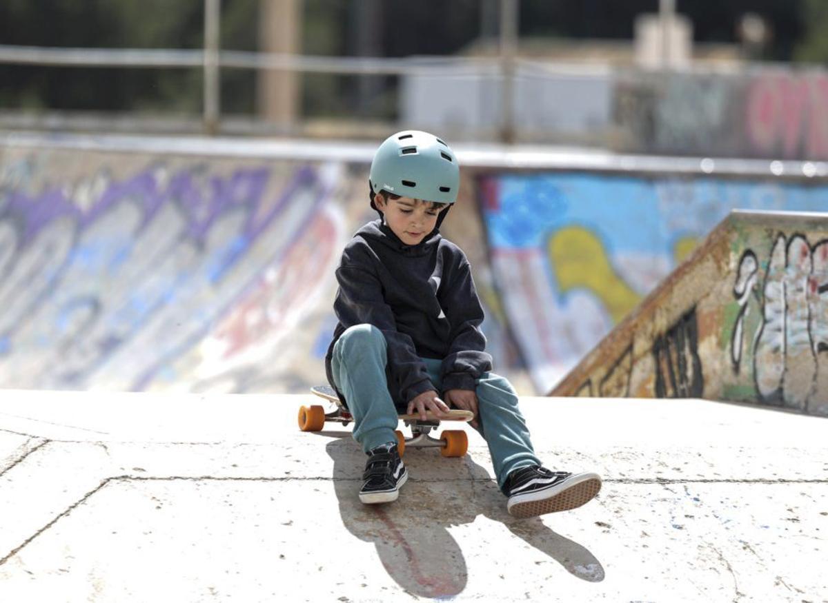 Un niño sentado sobre su tabla de ‘skate’. |