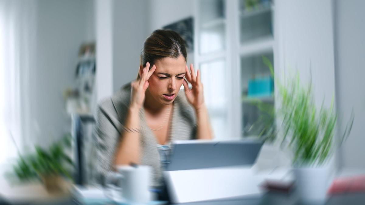 Una mujer se presiona las sienes para aliviar el dolor.