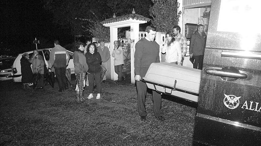 Personal de la funeraria retira el cadáver de la fallecida, ayer, ante la mirada de vecinos y allegados