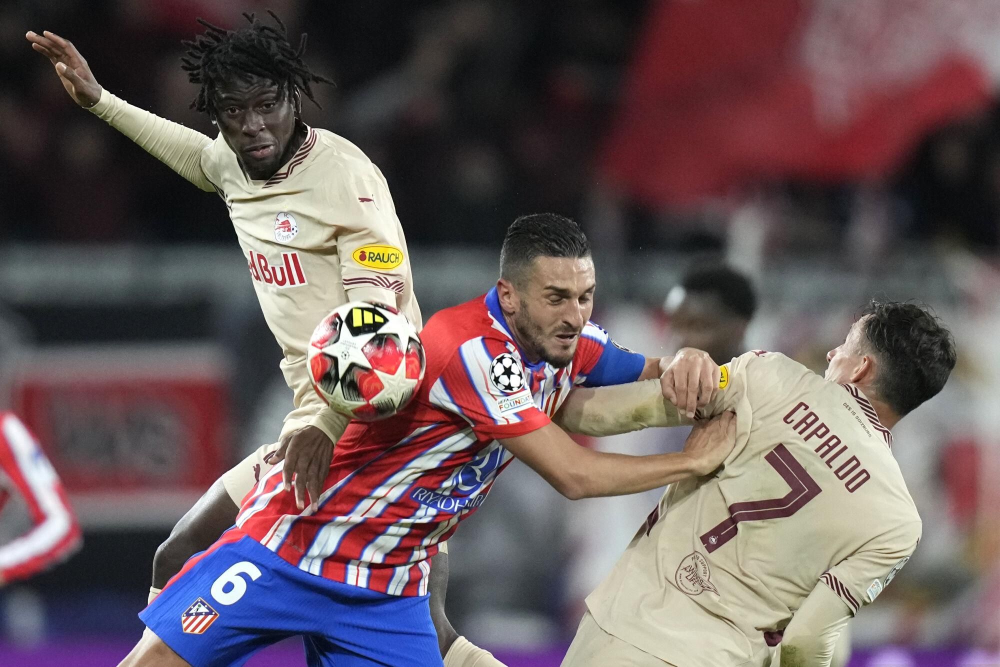 Salzburg's Moussa Yeo, left, and Atletico Madrid's Koke, center, and Salzburg's Nicolas Capaldo vie for the ball during the Champions League opening phase soccer match between FC Salzburg and Atletico Madrid at the Salzburg Arena in Salzburg, Austria, Wednesday, Jan. 29, 2025. (AP Photo/Matthias Schrader)