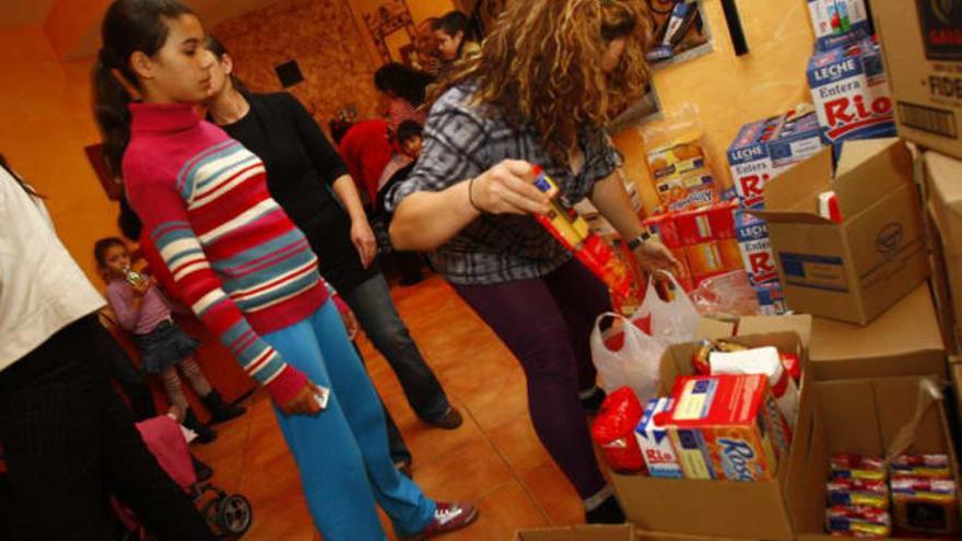 La demanda desbordó las previsiones. Abajo, los asistentes firman antes de recoger los alimentos.