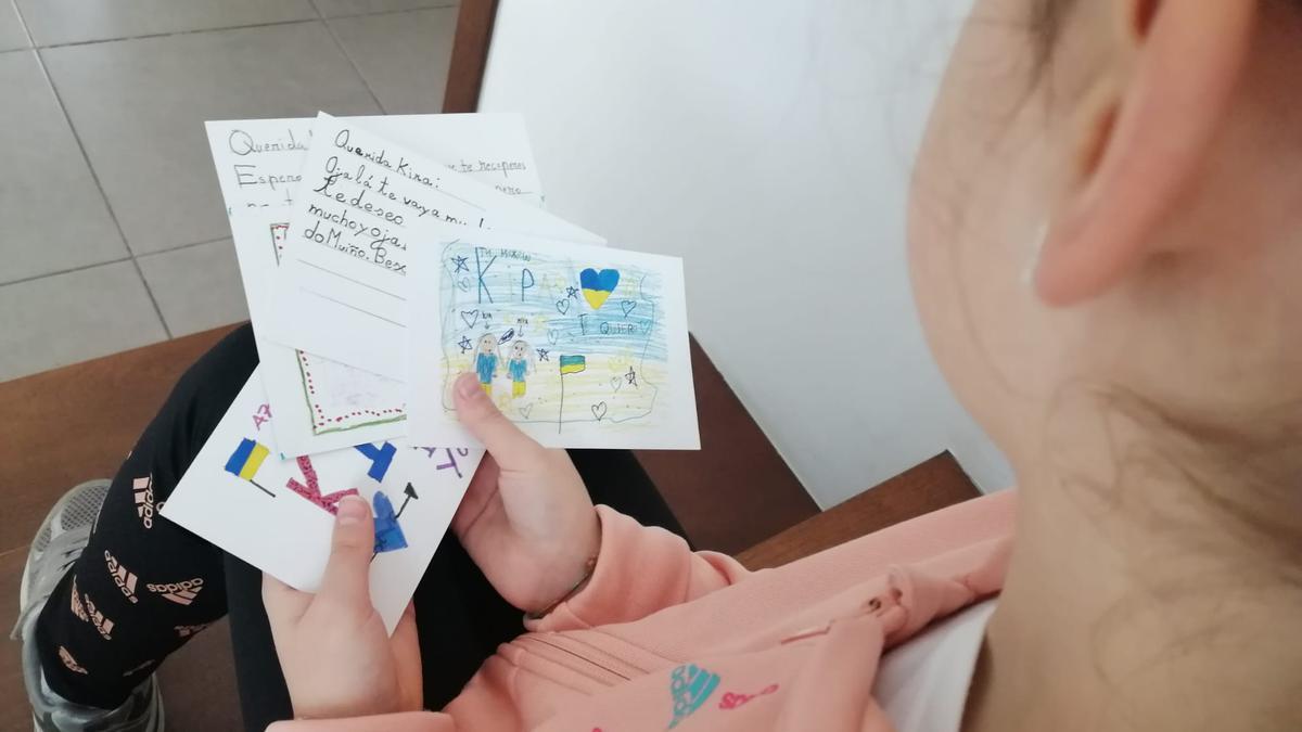 Una de las excompañeras de Kira sostiene postales confeccionadas para ser enviadas y recaudar fondos