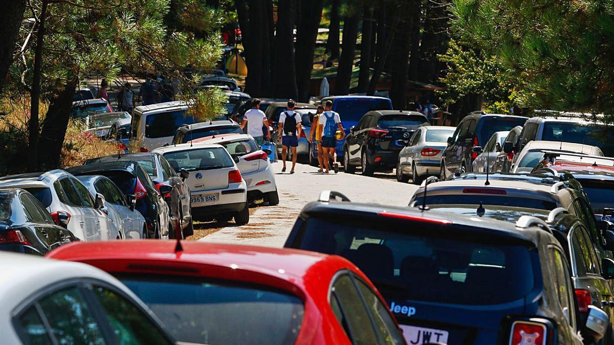 Cientos de coches llenan los accesos a la playa de Area da Secada cada día.