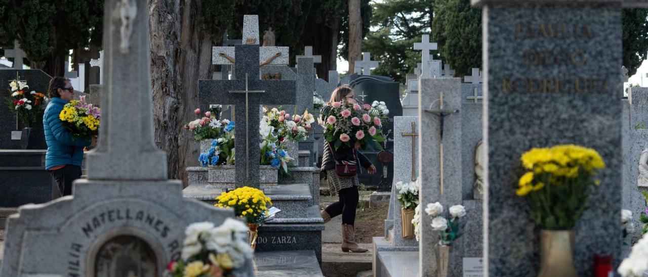 Dos mujeres llevan flores al cementerio este pasado 31 de octubre.