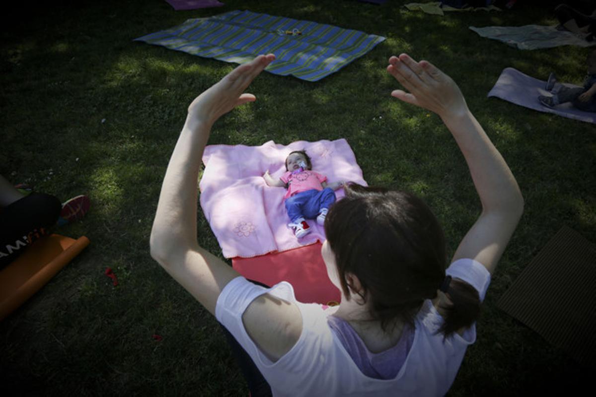 Una mare, amb el seu bebè, fa gimnàstica en un parc de Barcelona. Una mare, amb el seu bebè, fa gimnàstica en un parc de Barcelona.