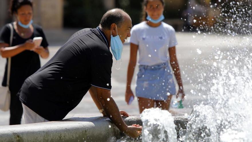 Un hombre se refresca en una fuente en Valencia.