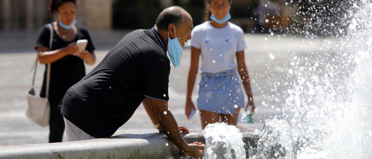 Un hombre se refresca en una fuente en Valencia.