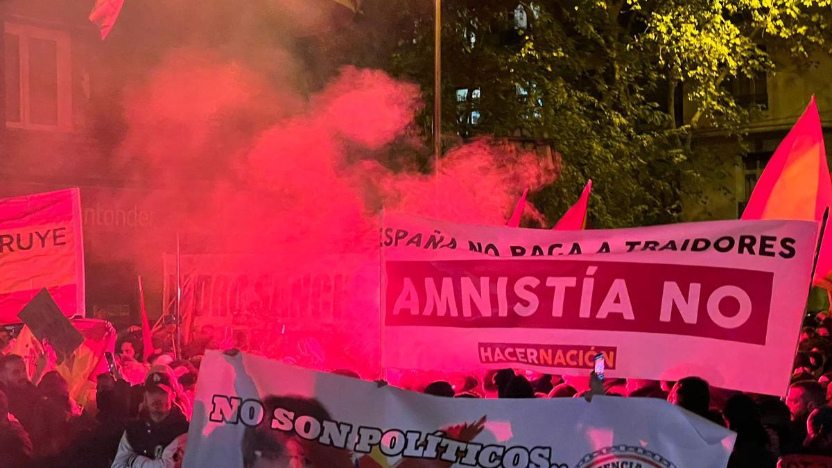 Pancartes contràries a l'amnistia envoltades de fum a prop de la seu del PSOE al carrer Ferraz de Madrid