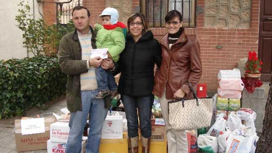 El hijo y la nuera de la agraciada, acompañados de la voluntaria que les vendió la papeleta, posan junto a algunos de los numerosos productos que contiene la cesta a las puertas de la sede de Cáritas en Toro