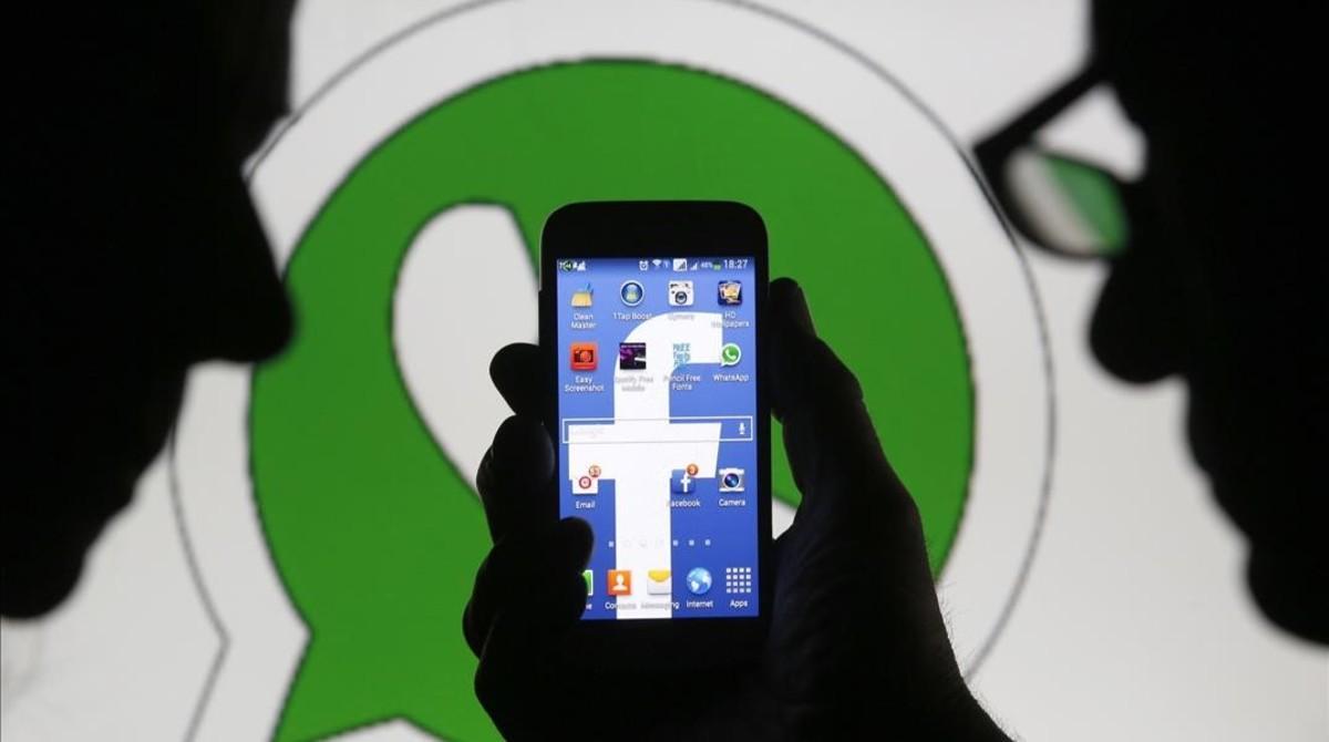 Dos usuarios ante los logos de Facebook en el móvil y Whatsapp. 
