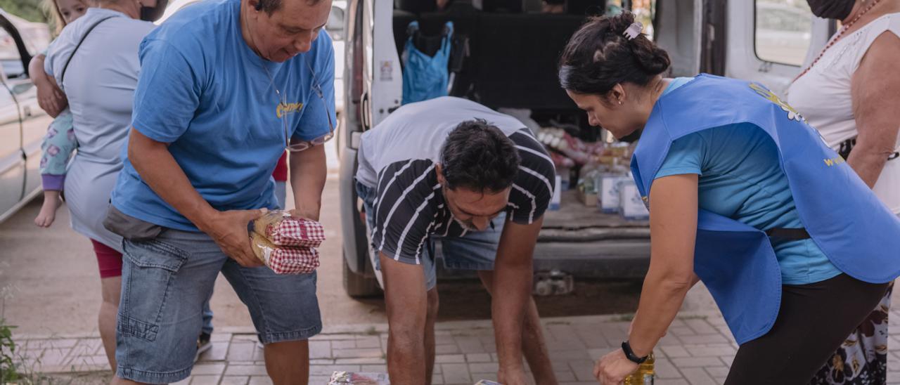 Voluntarios y beneficiarios de Inpavi trasladando paquetes de alimentos a un vehículo