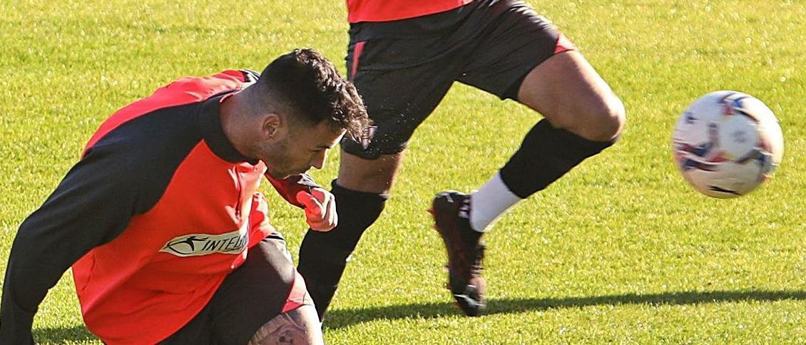 Álvaro Vázquez remata un balón en un entrenamiento en Mareo, ante la mirada de Carmona. | Juan Plaza