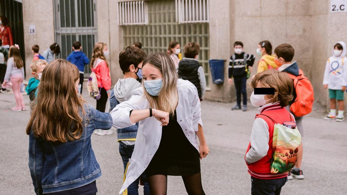 Profesora saludando con el codo a los alumnos