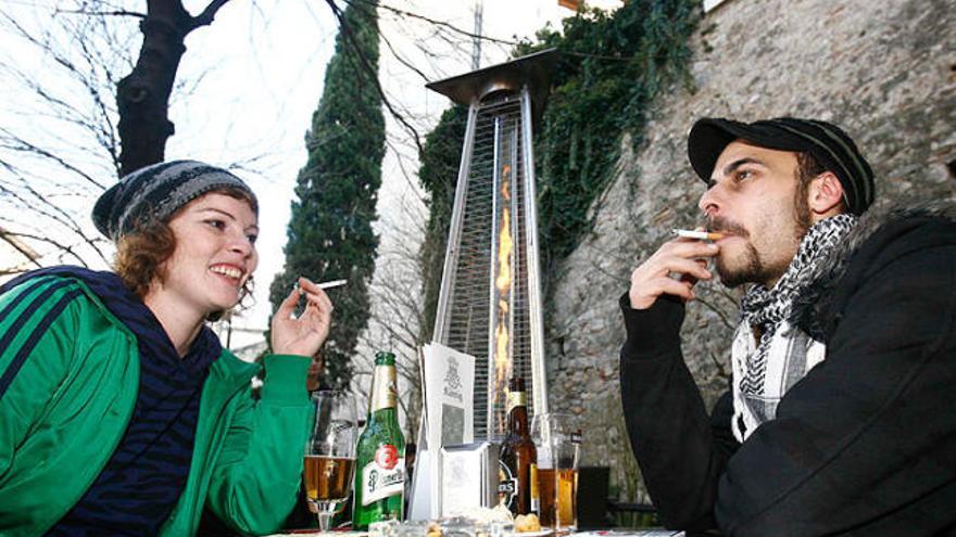 Dues persones fumen en una terrassa d&#039;un bar a la ciutat de Girona aquest gener.