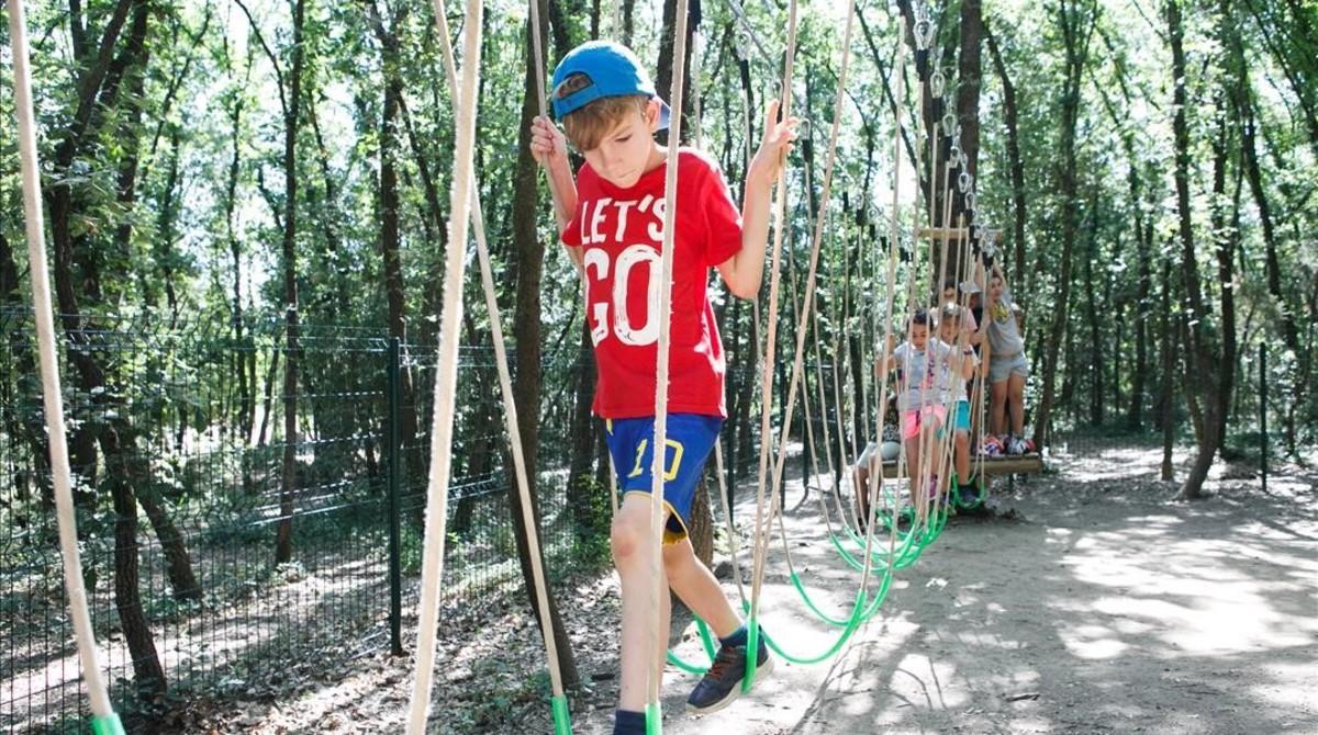 Unos niños recorren un puente colgante en La Granja de Santa Maria de Palautordera, en una actividad para ganar confianza y autonomía.