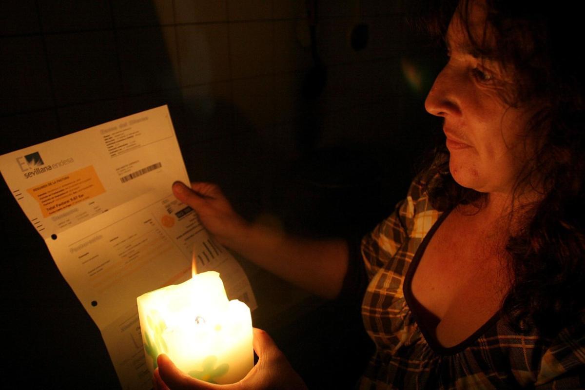 Vecina sin Luz en La Palma, lee un recibo de la Endesa a la luz de una vela, en una foto de archivo.