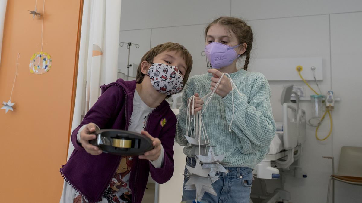 Ania, izda., y Martina, pacientes con tumor cerebral del hospital Vall de Hebrón en su tarea de decorar la planta infantil con 10.000 estrellas para guiar a los Reyes Magos a todos los niños ingresados