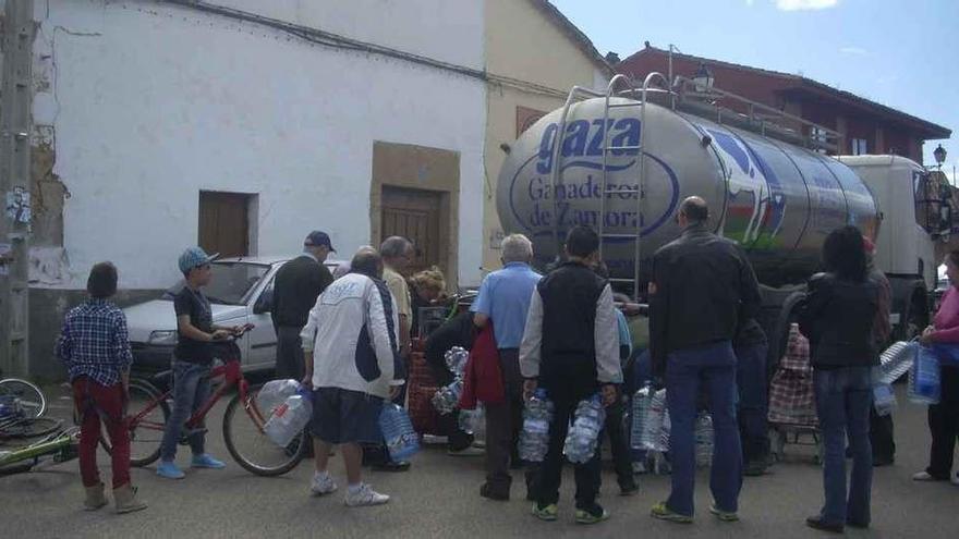 Vecinos de un municipio del alfoz cargan agua de un camión cisterna.