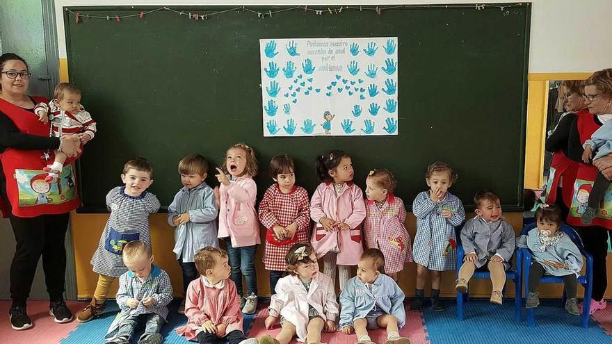 Un grupo de niños de la guardería, ante el cartel.