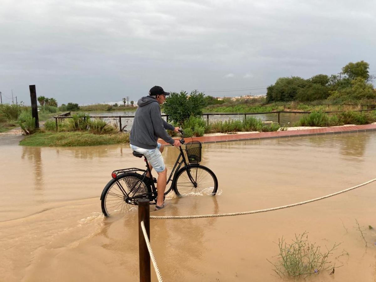 Un vecino de Las Torretas circula por la calle Golondrinas anegada de agua junto a las balsas de laminación esta semana