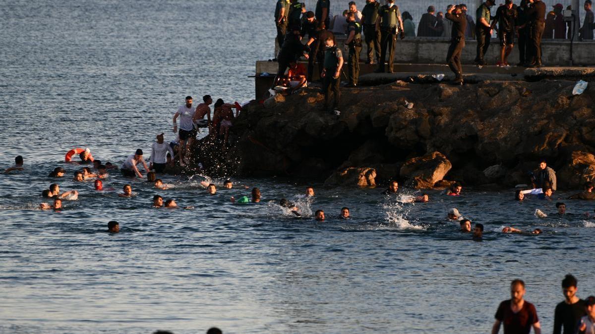 Personas migrantes caminan por la playa del Tarajal, en Ceuta, el pasado 17 de mayo de 2021.