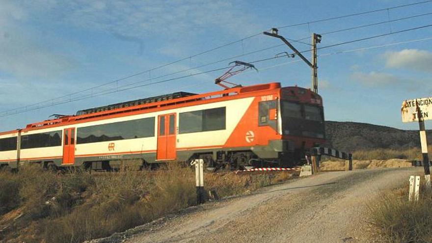 Un tren atraviesa un paso a nivel de la línea convencional de La Encina-Alicante a escasos metros de la estación de Monóvar.