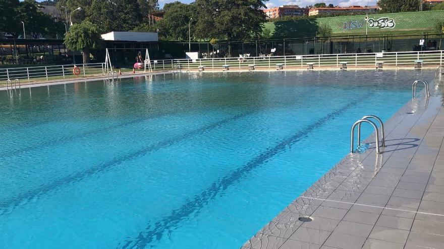 el vaso grande de la piscina municipal, desalojada, con una gran mancha verde al fondo.