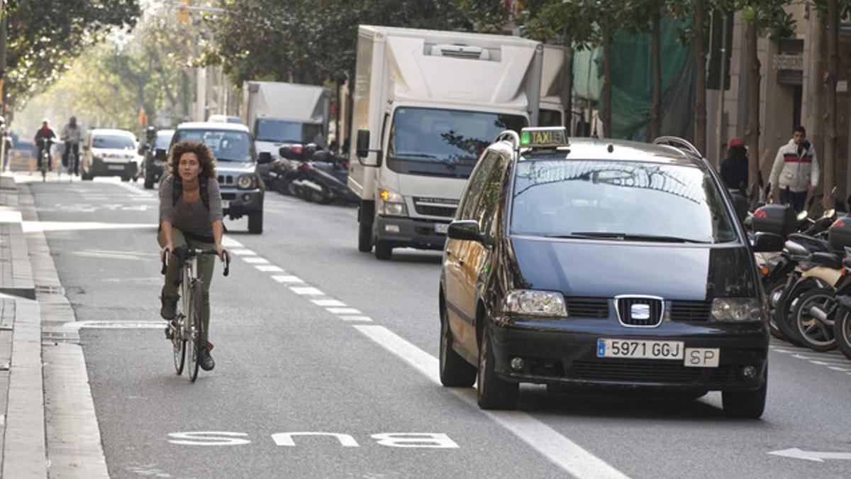 Una ciclista, y otros dos al fondo, suben por Gran de Gràcia hacia la plaza de Lesseps, ayer por la mañana, ocupando el carril bus-taxi.