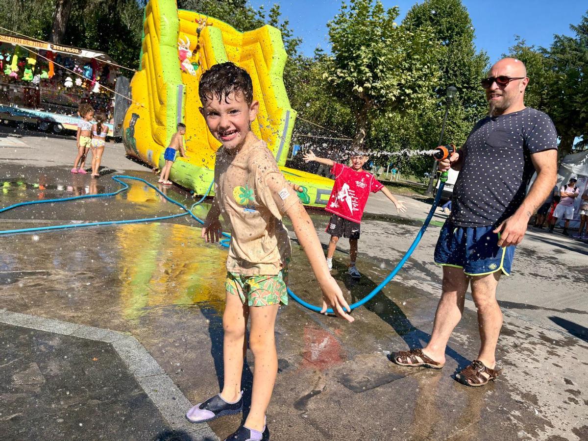 Un niño se divierte con el agua en la jira de las fiestas de Santiago en Sama