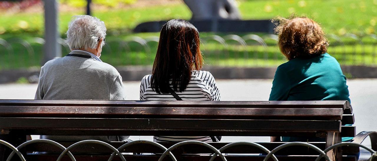 Personas mayores descansando en un banco en compañía de una joven. | |