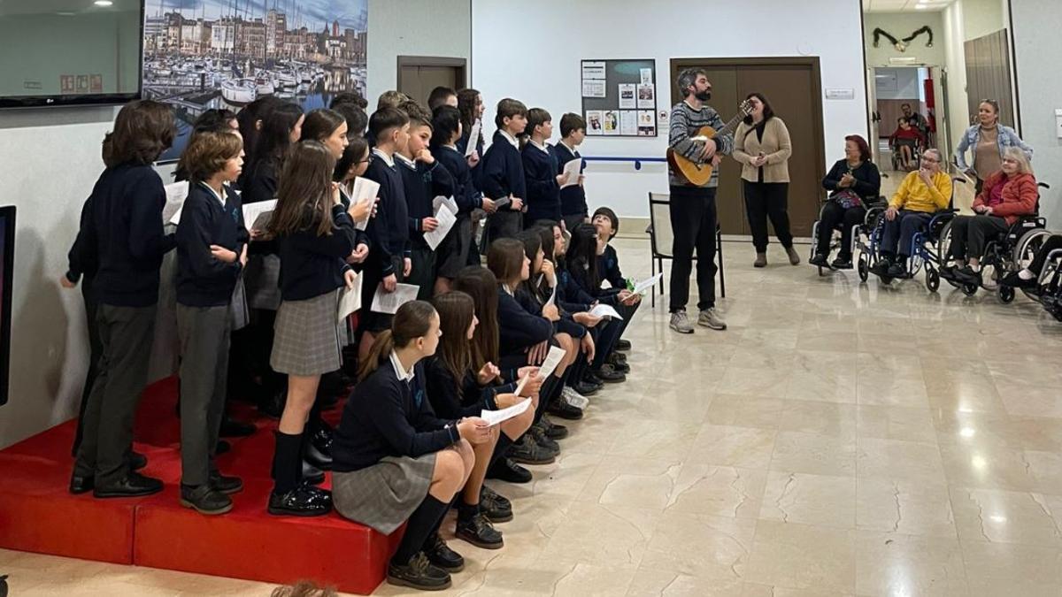Los alumnos del Colegio Santo Ángel, cantando villancicos a los mayores de la residencia Plaza Real de Gijón.