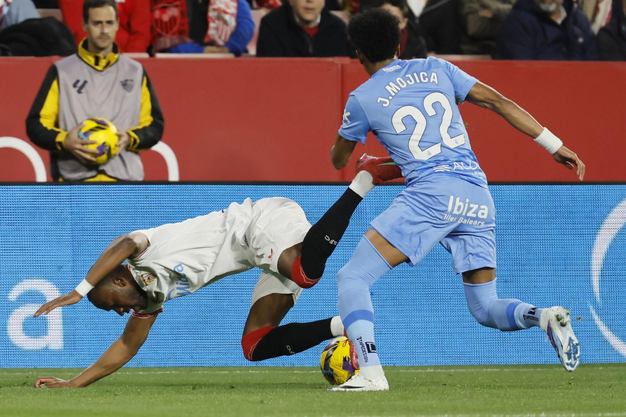 El delantero del Sevilla Dodi Lukébakio (i) cae ante Johan Mojica, del Mallorca, durante el partido de LaLiga de fútbol que Sevilla FC y RCD Mallorca disputan en el estadio Ramón Sánchez-Pizjuán. EFE/José Manuel Vidal. (Sevilla) (Mallorca)