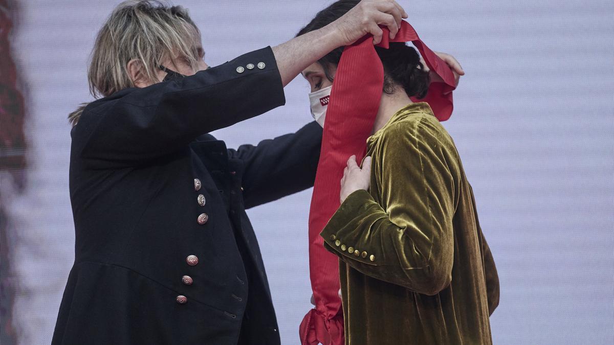 El compositor Nacho Cano devuelve a Isabel Díaz Ayuso la Gran Cruz de la Orden del Dos de Mayo después de que ella se la entregara a él, en la Real Casa de Correos de Madrid, con motivo del Día de la Comunidad.