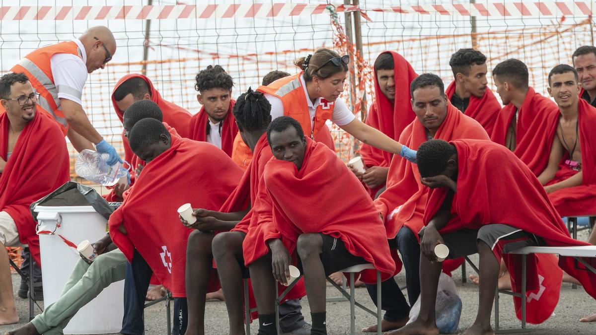 Un grupo de personas llegadas en barcazas son atendidas por la Cruz Roja.