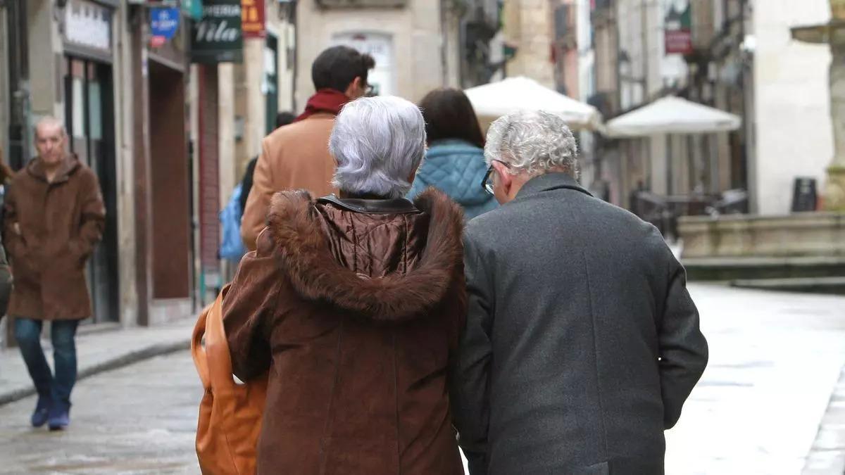 Dos pensionistas pasean por una calle.