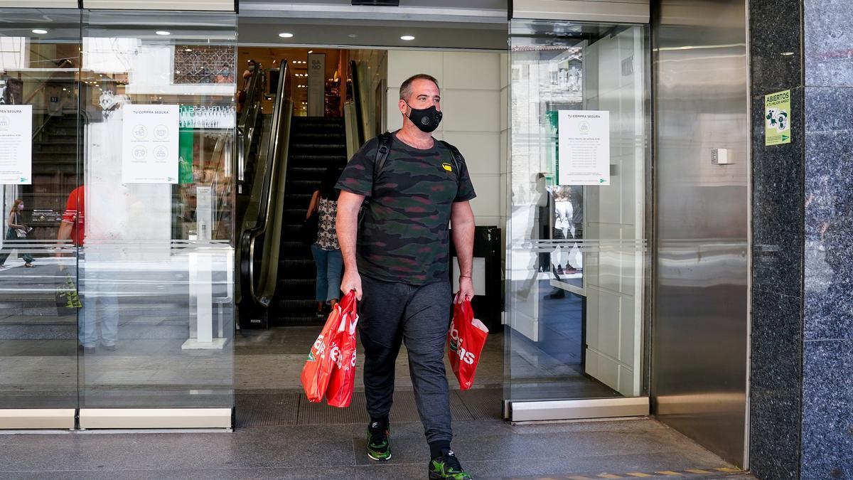 Un hombre sale con varias bolsas de un establecimiento de Madrid.