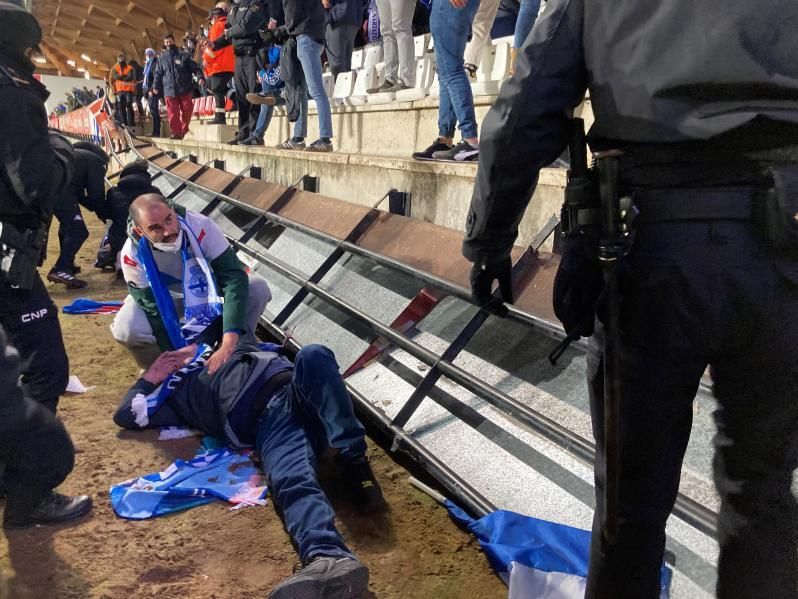 Un aficionado blanquiazul auxilia a otro tras la caída.