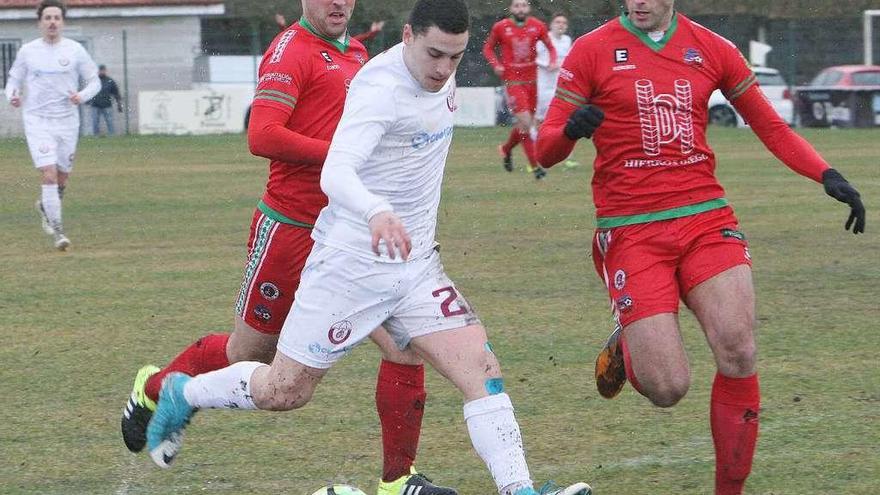 Un jugador del Nogueira controla un balón ante dos jugadores del Estradense. // Iñaki Osorio