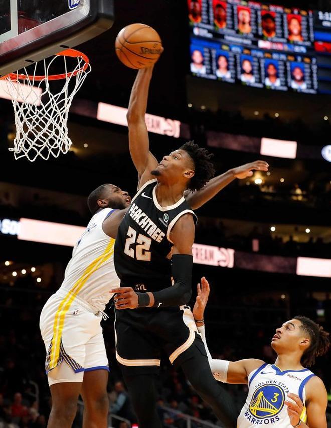 Cam Reddish # 22 de los Atlanta Hawks no se conecta en esta volcada contra Eric Paschall # 7 y Jordan Poole # 3 de los Golden State Warriors en la segunda mitad en State Farm Arena en Atlanta, Georgia.