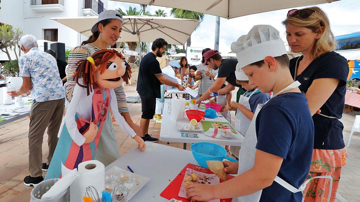 Aina Zuazaga y la Xef Pipa observan cómo elabora los ‘panellets’ uno de los jóvenes asistentes al taller de cocina.