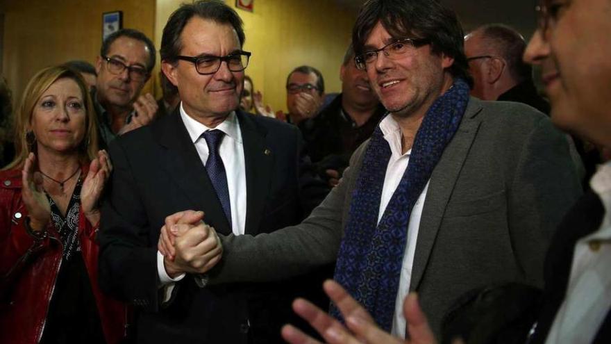 Mas estrecha la mano de Puigdemont, a su llegada a la sede de CDC, después de que el primero anunciara su renuncia a ser candidato. // Efe