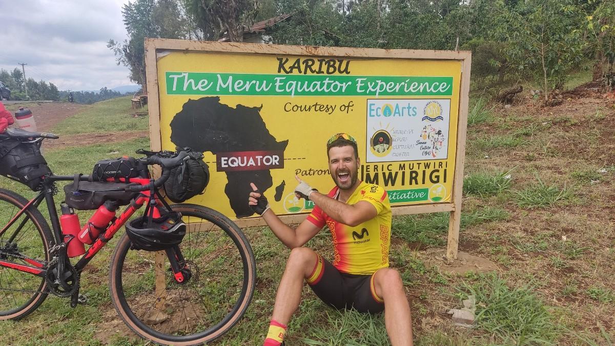 Juanma Mérida, en su aventura de cruzar África en bicicleta, posando con el cártel de la línea del ecuador