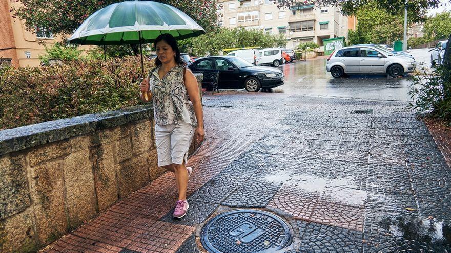 Una mujer pasea por una calle de Cáceres mientras llueve en la ciudad.