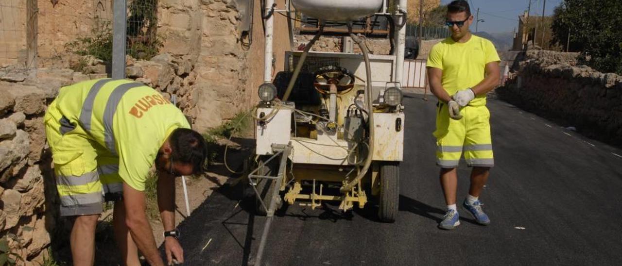 Operarios contratados por el Consell pintan las marcas viales de la nueva carretera.